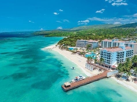 ジャマイカのオーチョ リオスの中心部に位置する、260 室の豪華な客室を備えたまったく新しいサンダルズ ダンズ リバーの空撮 - 画像提供：サンダルズ