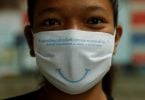 Amazing Thailand welcomes visitors with a beautiful smile behind a face-mask